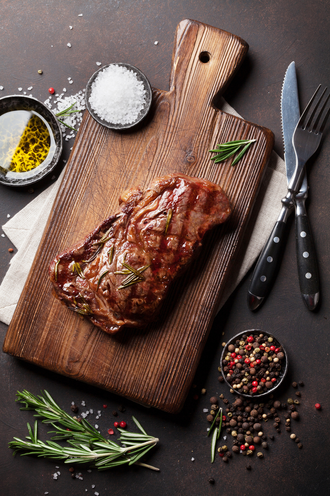 Grilled ribeye steak on a cutting board.