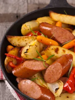 Sausage in a frying pan with vegetables.