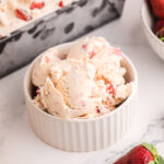 Strawberry ice cream in a small white bowl.
