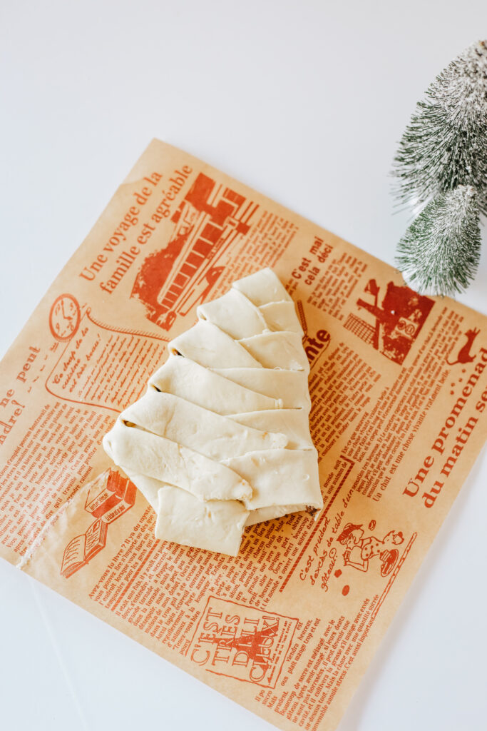 Puff pastry with a chocolate christmas tree in the center. The puff pastry is cut on the sides and bottom and is being folded over the chocolate. 