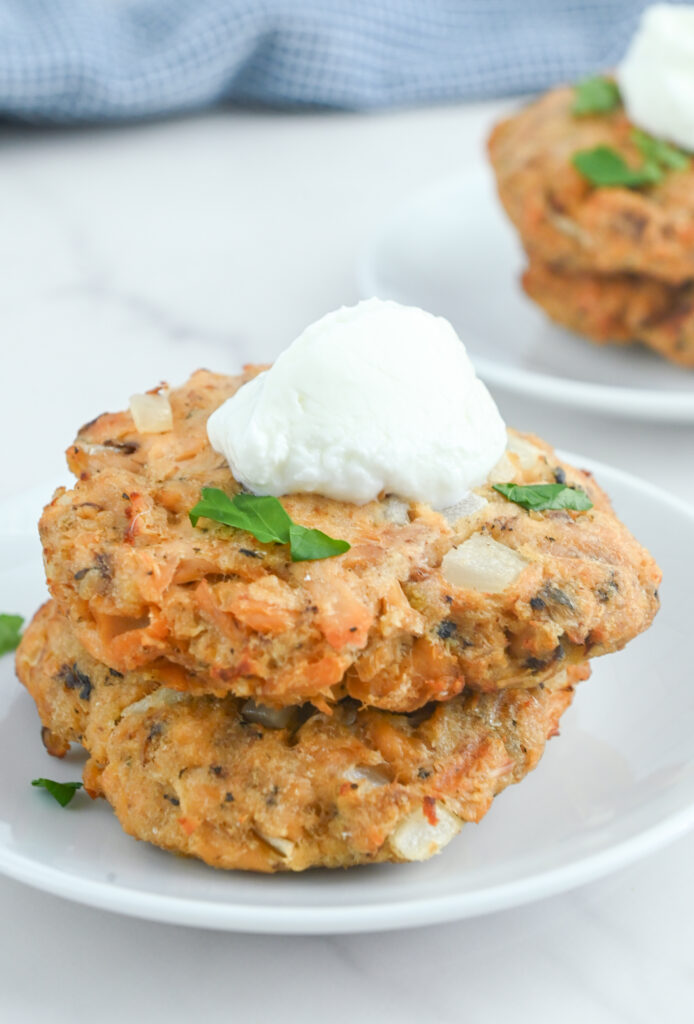 Air fryer salmon patties stacked on top of each other with a dollop of sour cream on top. 