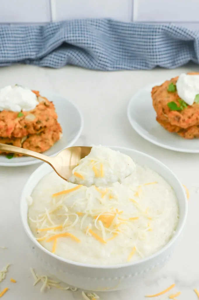 Grits in a bowl next to salmon patties.