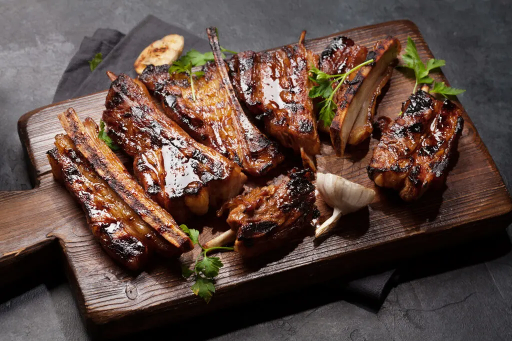 Barbecue beef ribs with bbq sauce sliced on a wooden board