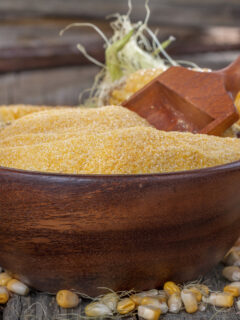 corn grits polenta in a wooden bowl on old wooden table