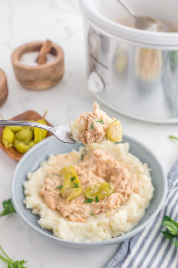 Crock Pot Mississippi Chicken Recipe in a bowl on top of mashed potatoes.
