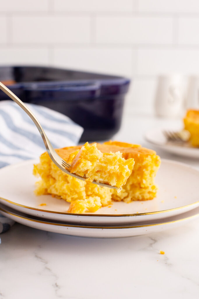 the ultimate cornbread casserole on a plate. There's a fork with some on it. 
