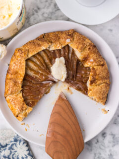 Caramel pear galette on a white plate with a spatula.