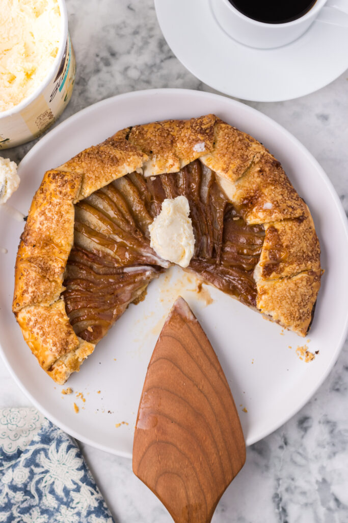 Caramel pear galette on a white plate with a spatula.