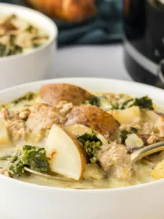 Soup in a white bowl with potatoes.