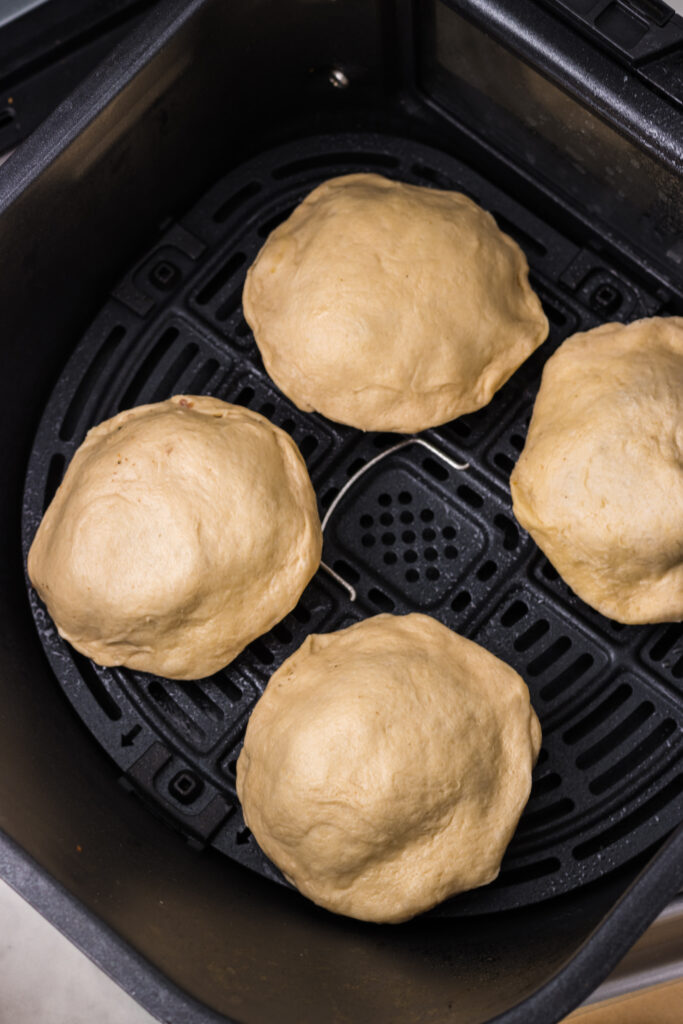 Uncooked biscuits in an air fryer basket. 