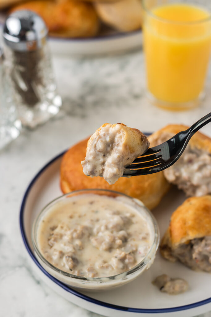 Dipping sausage biscuits into gravy